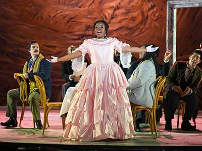 Melissa performing on stage wearing elaborate pink dress.